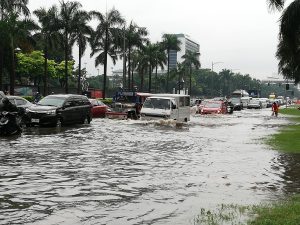 flooded urban street, with vehicles and motorcycles navigating through the water